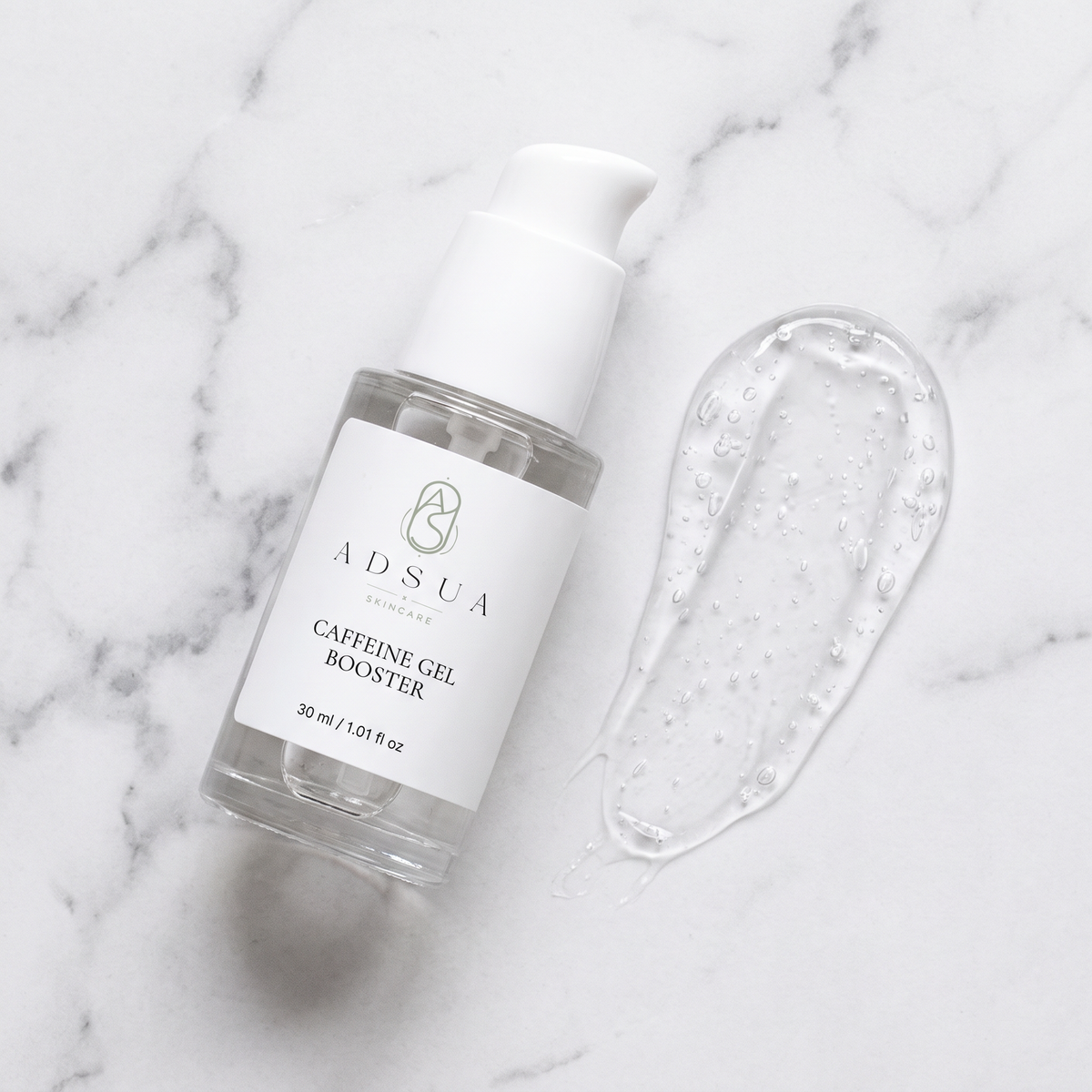 Adsua Caffeine Gel Booster op wit marmer met een heldere gelveeg met luchtbelletjes
