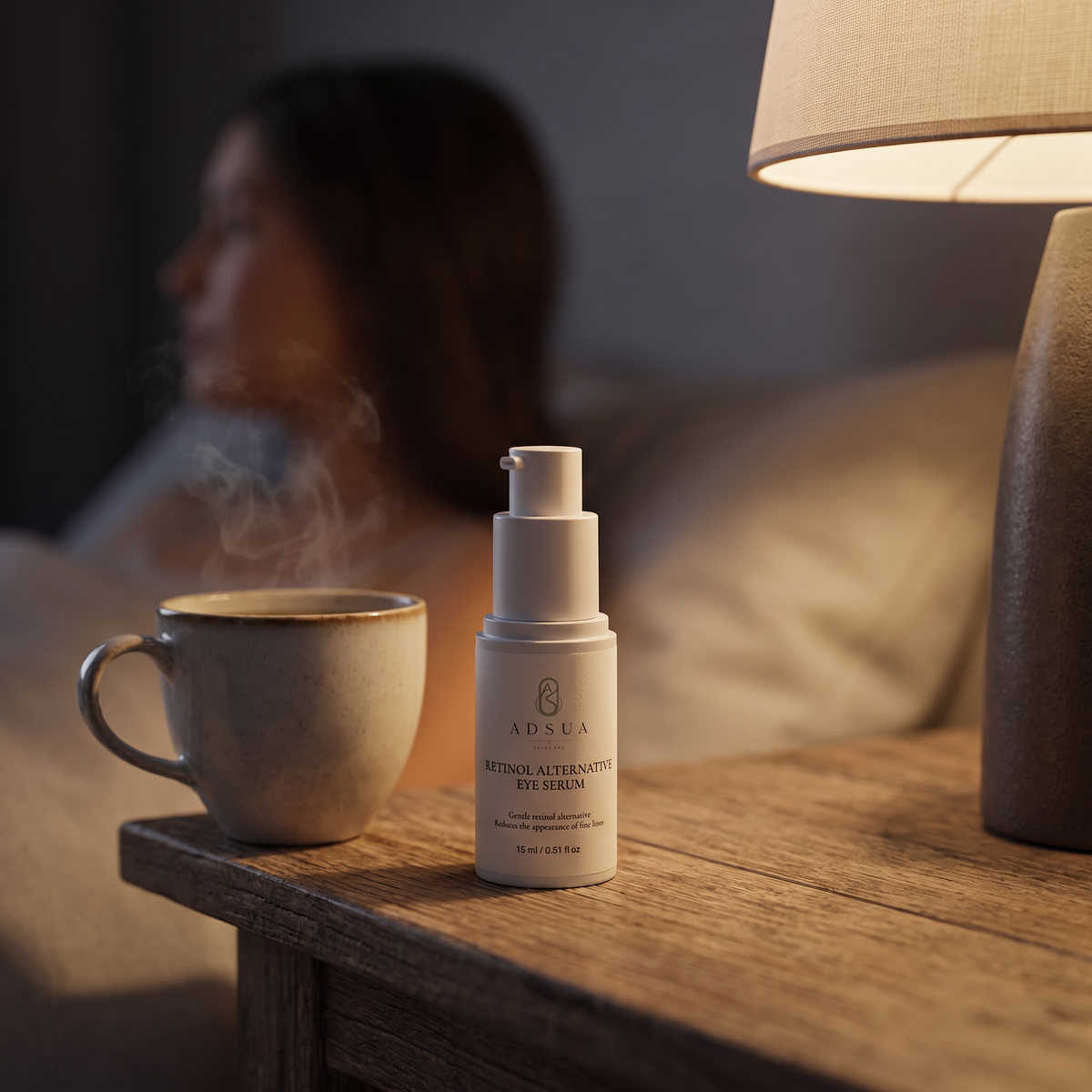 Adsua Retinol Alternative Eye Serum op het nachtkastje naast een kop thee, met een vrouw op de achtergrond