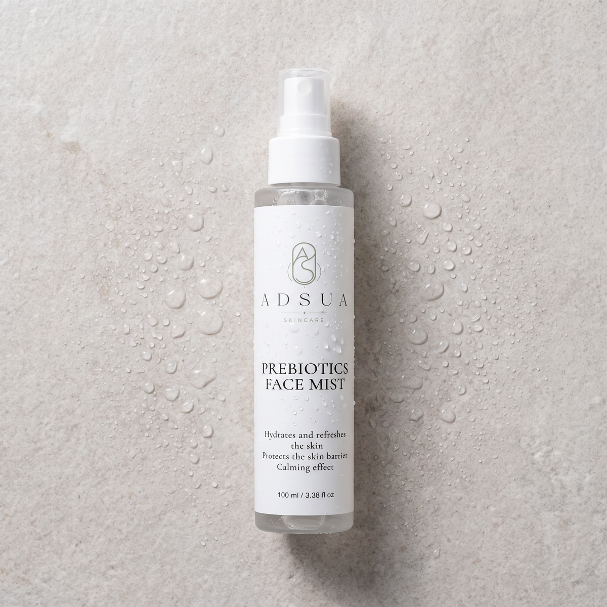 Adsua Prebiotics Face Mist op lichtgrijze steen met waterdruppels