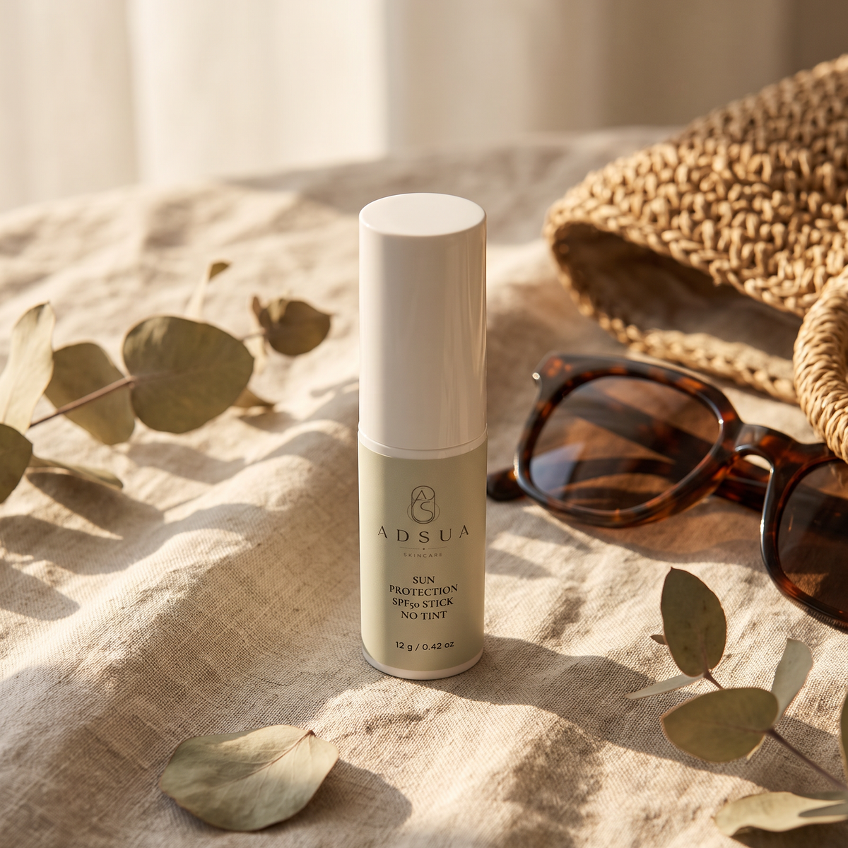 Adsua Sun Protection SPF50 Stick op linnen naast een zonnebril en een gevlochten strotas