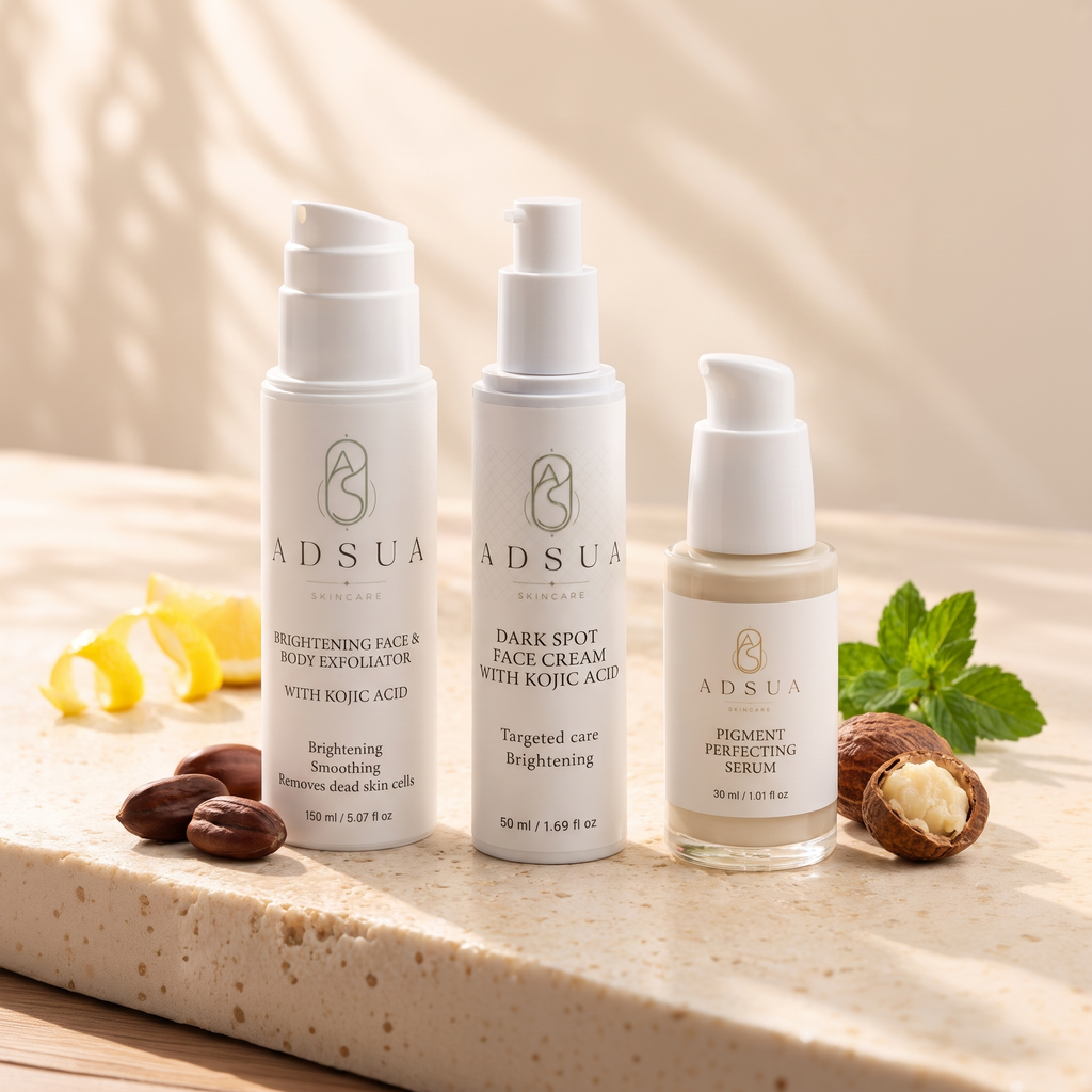 De Adsua dark spot routine in de zon: de Brightening Face & Body Exfoliator, de Dark Spot Face Cream met kojiczuur en het Pigment Perfecting Serum op travertijn, met jojobazaadjes en een sheanoot